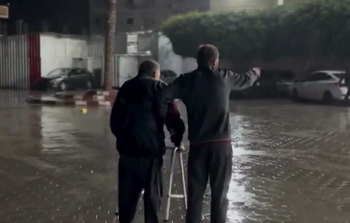 Thumbnail preview image for the video titled: Elderly walks with walking frame to hospital under heavy rain