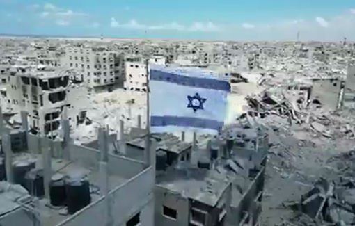 Thumbnail preview image for the video titled: Large Israeli flag hoisted over the rubble of Yabna camp, Rafah